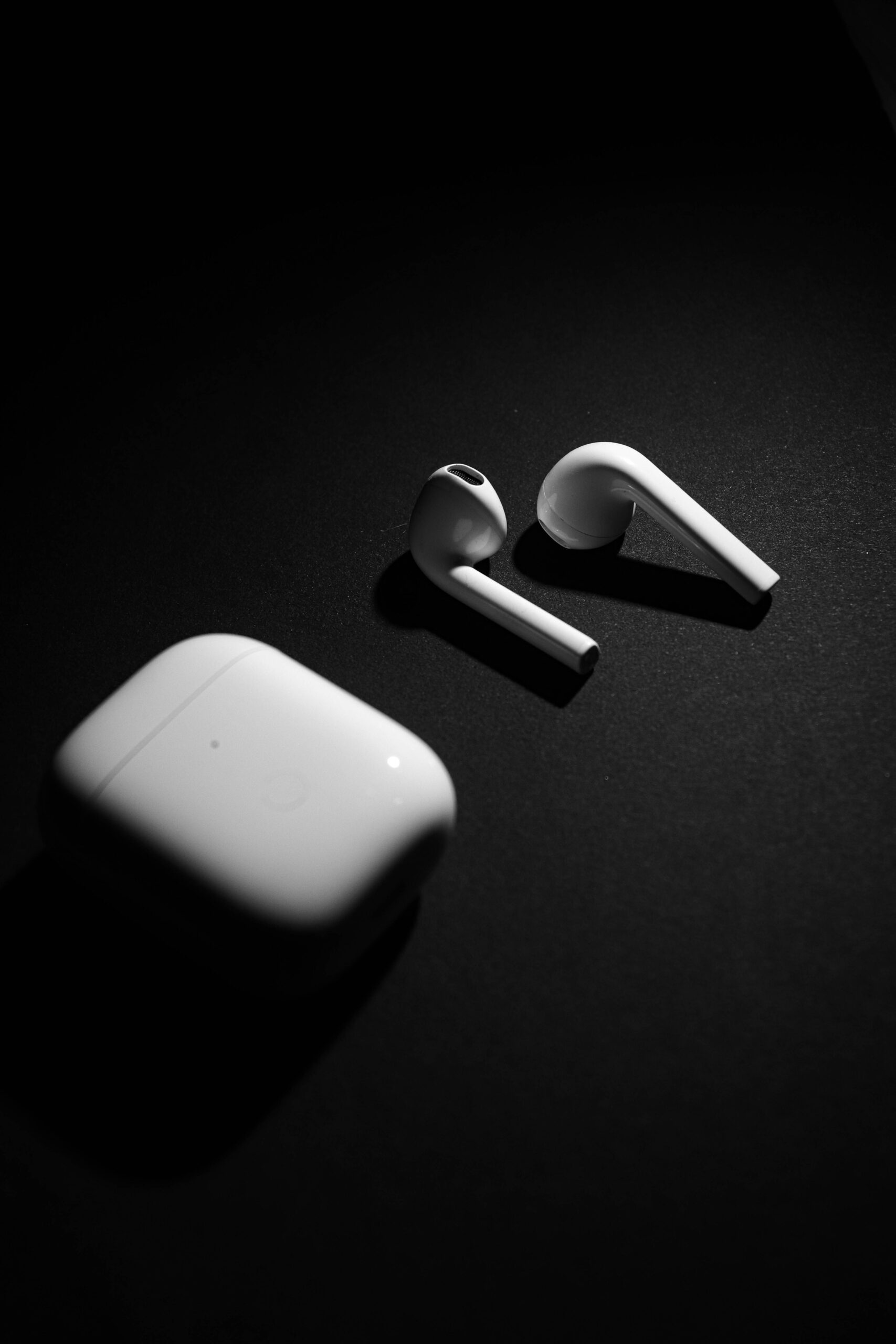 white wirless earbuds with charging case on a black baground