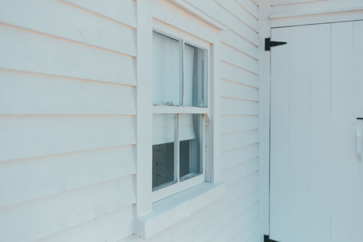 Siding repair or replacement: close-up of white wooden siding around a window and door